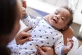 Happy three month old baby boy lying on his back on his motherÃ¯Â¿Â½s knee looking up at her, over shoulder view, close up Royalty Free Stock Photo